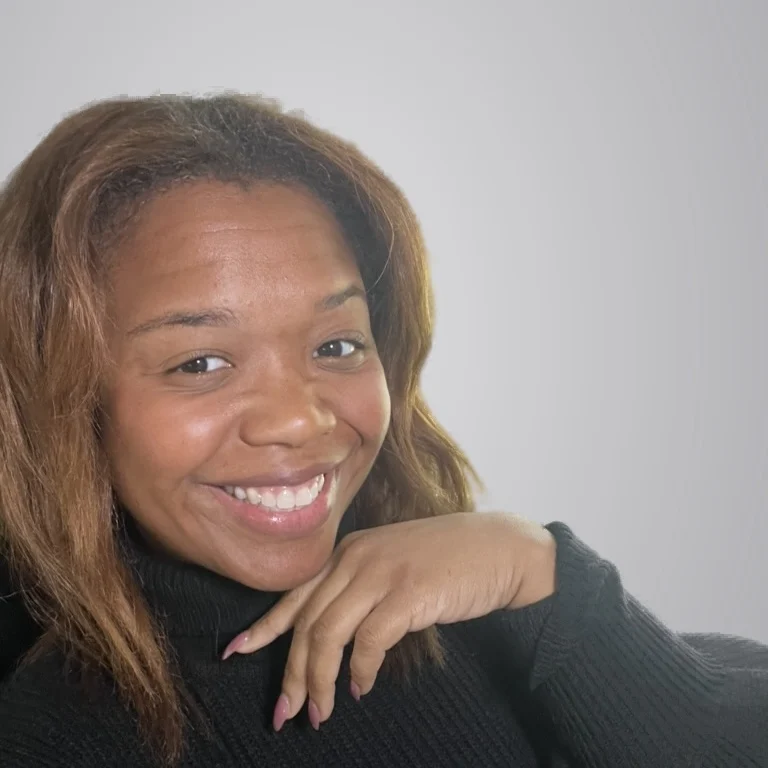 Dr. Sheilesha Willis smiling, chin resting on her hand, in a black turtleneck